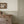 Mia wallpaper by Curate Space in olive green, rows of dots forming a stripe in a bedroom above a wooden chest of drawers