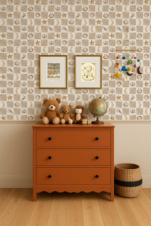 Molly wallpaper by Curate Space in beige, seashells and seahorses on a check in a nursery with an orange chest and teddy bears