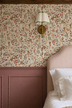 Nola wallpaper by Curate Space in off-white, wildflowers and tall stems in a bedroom with pink panelling and a brass wall sconce