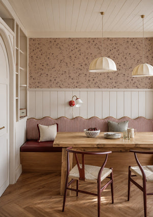 Paloma wallpaper by Curate Space in dark pink, trailing floral stems above panelling in a dining nook with a banquette