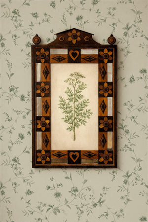 Paloma wallpaper by Curate Space in soft green, close-up of trailing floral stems behind a decorative inlaid mirror