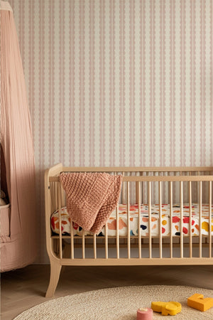 Rosalie wallpaper by Curate Space in soft pink, a scalloped stripe in a nursery with a wooden cot