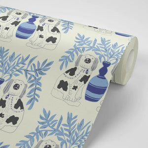 Pair of Dogs wallpaper by Annika Reed in blue, partly unrolled roll showing pairs of dogs and vases