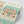 Pair of Dogs wallpaper by Annika Reed in mint green and brown, roll showing pairs of dogs and vases
