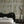 Eden wallpaper by Deus ex Gardenia in cream and green, lush leaves and fruit behind a bed