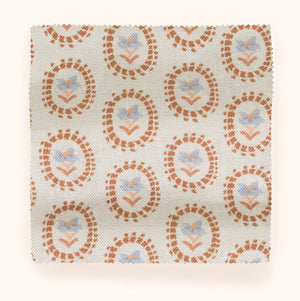 Folly linen by Parker and Jules in cream and orange, in soft folds showing sunburst medallions
