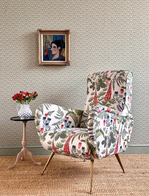 Folly wallpaper by Parker and Jules in brown, small sunburst medallions behind a sofa in a living room