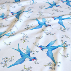 Forget Me Not Swallow fabric by Seed Home Designs in blue and white, draped, showing swallows and forget-me-nots