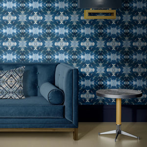 Indigo Itajime wallpaper by Tatie Lou in blue, itajime shibori folds behind a sofa in a living room