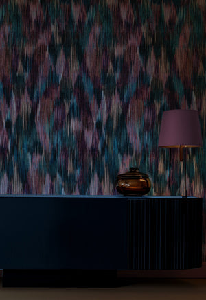 Spectre Ikat wallpaper by Victoria Sanders in berry pink, a blurred ikat design behind a console table