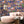 Mayhem Mansion wallpaper by Brand McKenzie in blue, animals partying in a mansion behind a sofa in a living room