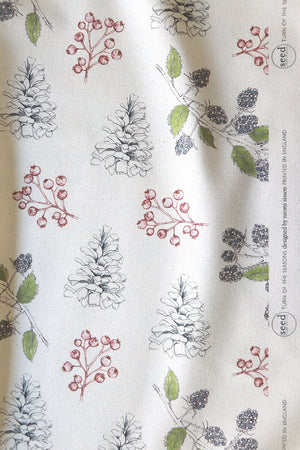 Organic Turn of the Seasons Pinecone and Berry linen by Seed Home Designs in green and red, draped, showing