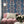 Paradise Party wallpaper by Brand McKenzie in navy, a mirrored tropical party scene behind a sofa in a living room