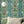 Paradise Party wallpaper by Brand McKenzie in green, a mirrored tropical party scene on a living room wall