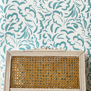 Pia wallpaper by Claire de Quénetain in light green, scattered leaves in a styled room setting