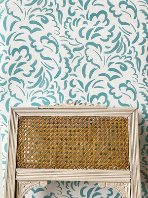 Pia wallpaper by Claire de Quénetain in light green, scattered leaves in a styled room setting