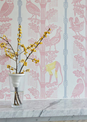 Monkeys and Birds wallpaper by St. Jude's in pink, monkeys and birds on stems behind a console table