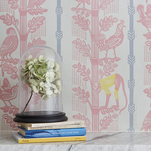 Monkeys and Birds wallpaper by St. Jude's in pink, monkeys and birds on stems above a sideboard