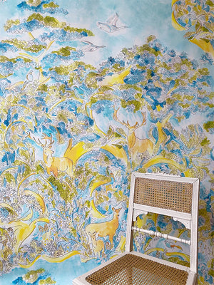 Reve D’Enfant wallpaper by Claire de Quénetain in green and orange, a hand-painted floral design in a styled room setting