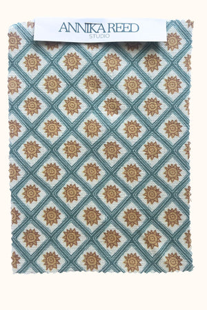 Solstice Sun linen by Annika Reed in blue and orange, pattern sample of suns in a lattice