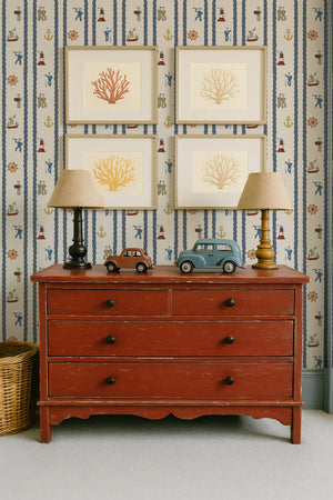 Stow Away With the Sailors wallpaper by Annika Reed in blue and red, sailors and boats above a sideboard