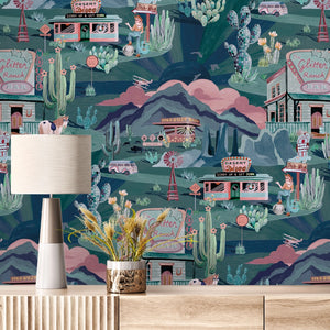 The Glitter Ranch wallpaper by Brand McKenzie in cream and pink, a desert ranch scene behind a console table